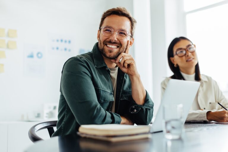 Business man listening to a discussion during a meeting in an office. Happy business man sitting in a boardroom with his colleagues.